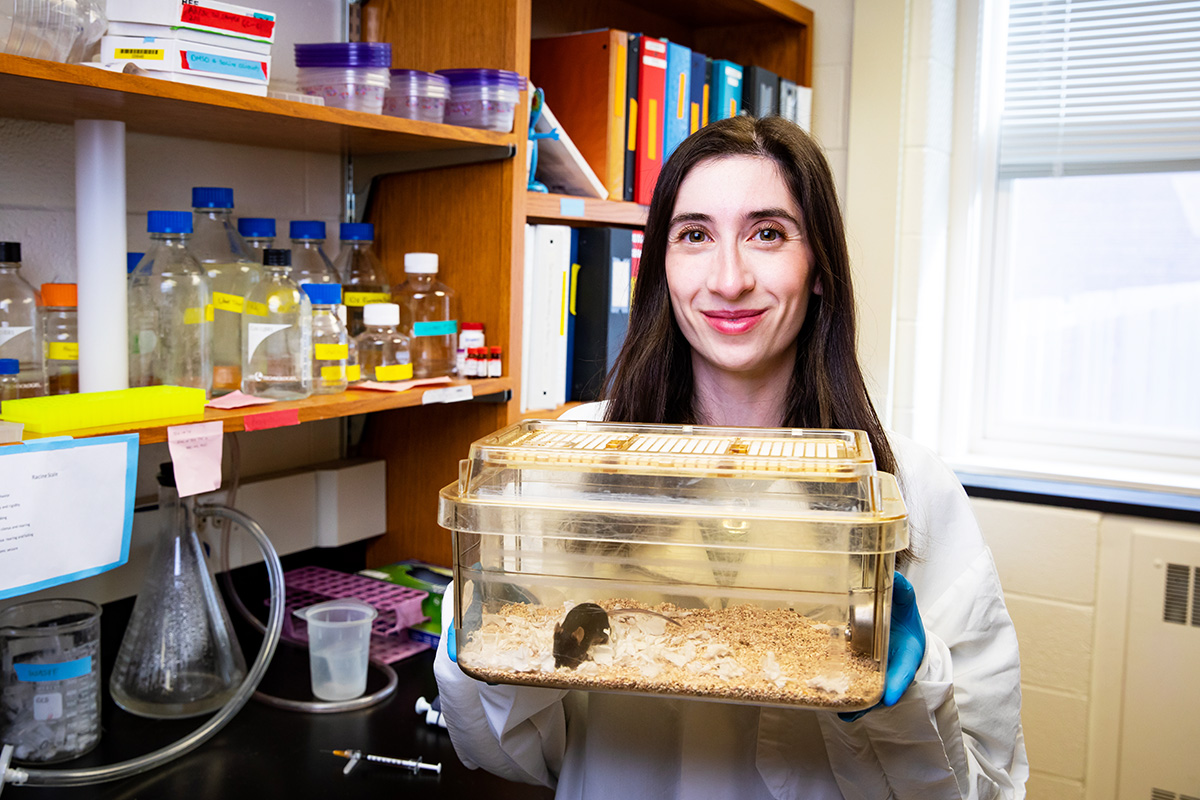 U. of I. doctoral candidate Jennifer Walters stands in the Chung Lab holding a mice habitat with one mouse in it. 