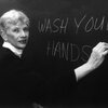 Microbiologist Dixie Whitt writes on a chalkboard, "Wash your hands."