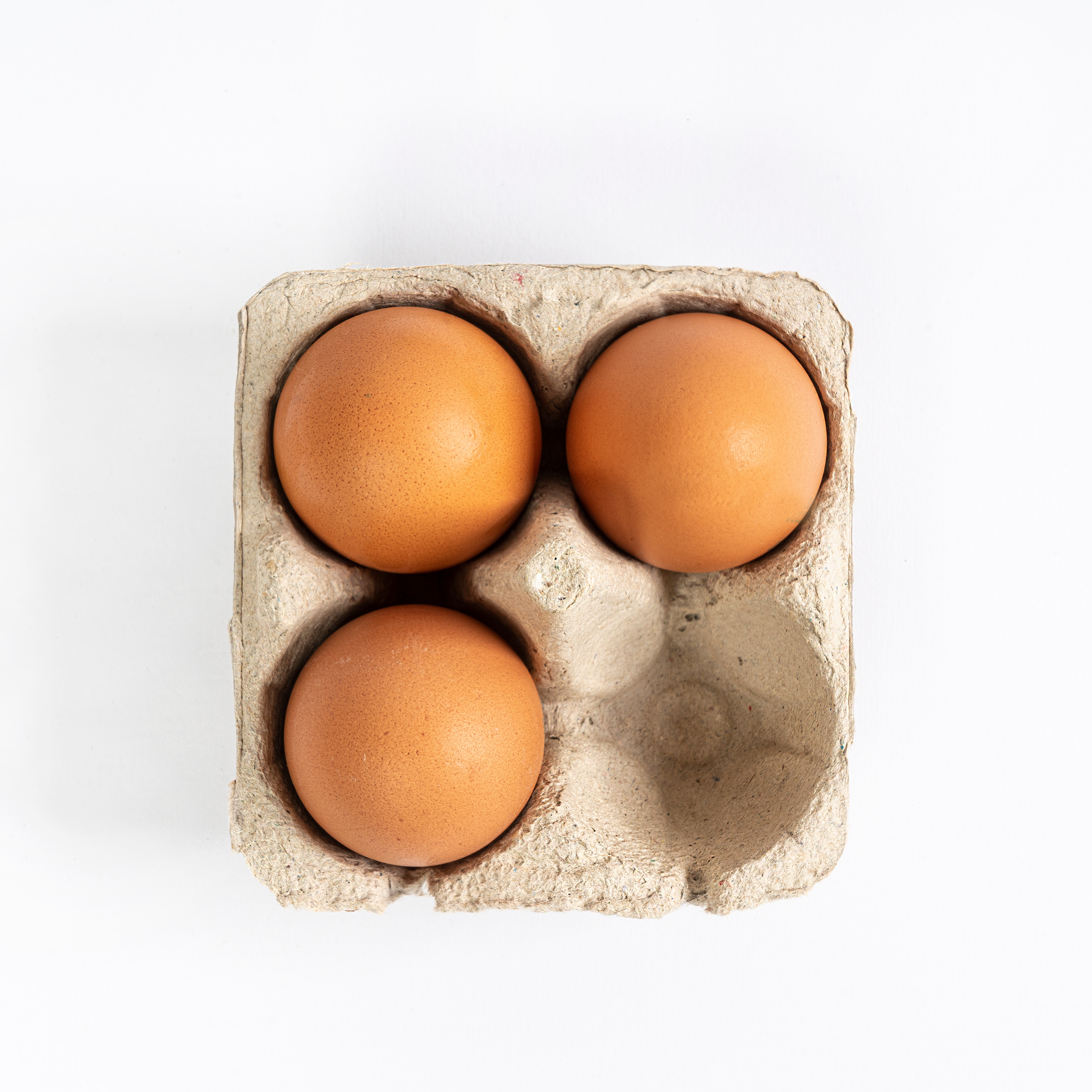 Flat lay shot of three eggs in a container that can hold up to four.