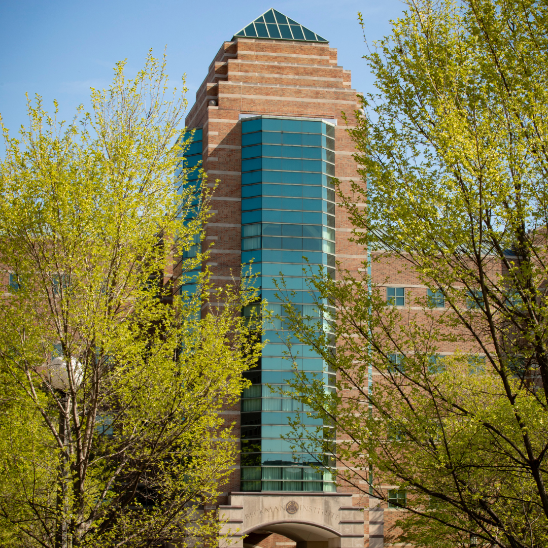 Beckman Institute tower framed by blooming trees.