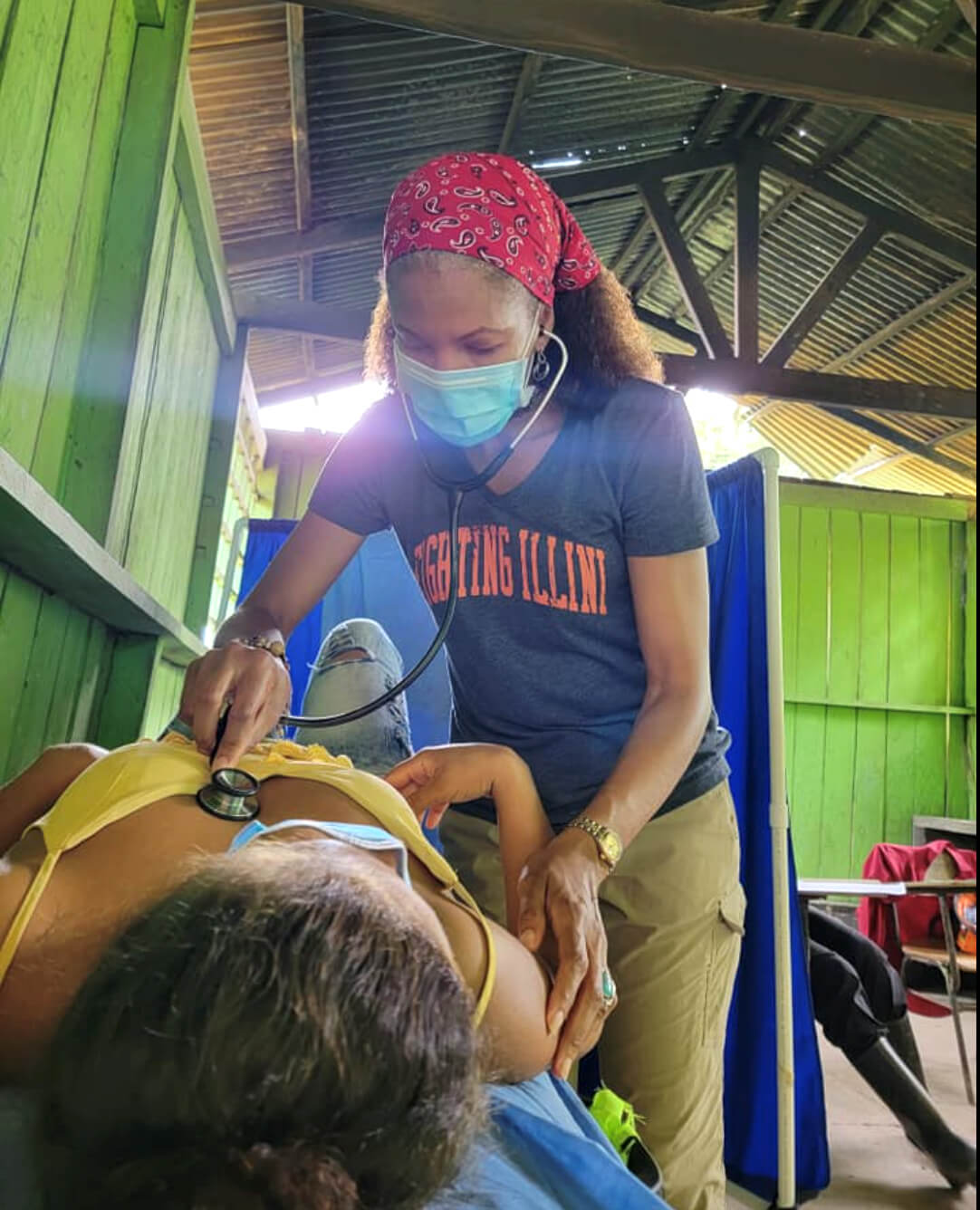 Dr. Nicole Williams, masked, checks a woman's heart rate with a stethoscope on a medical mission to the Peruvian Amazon.