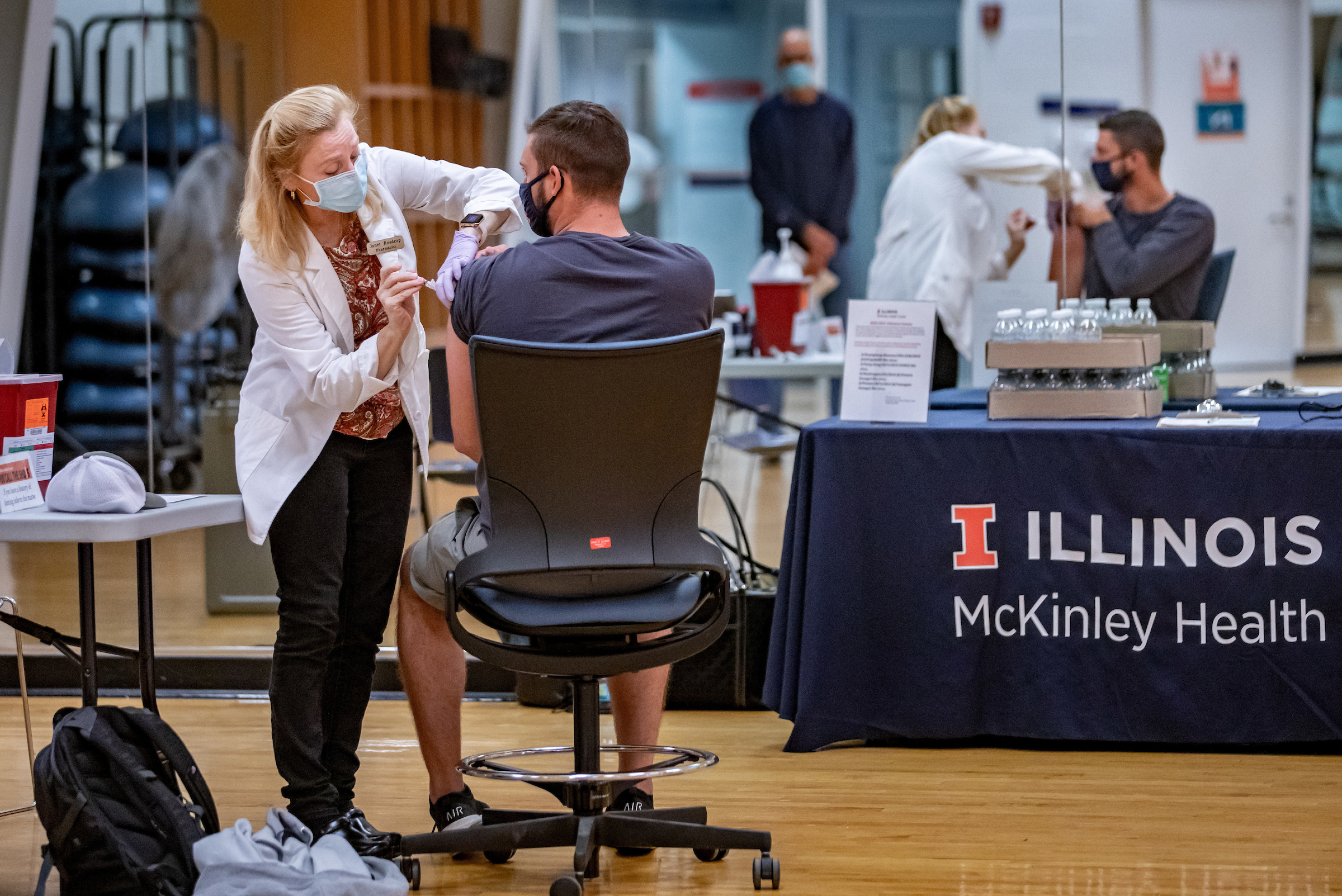 Person in mask gives student a flu shot at a flu shot clinic provided by McKinley Health Center at the University of Illinois.