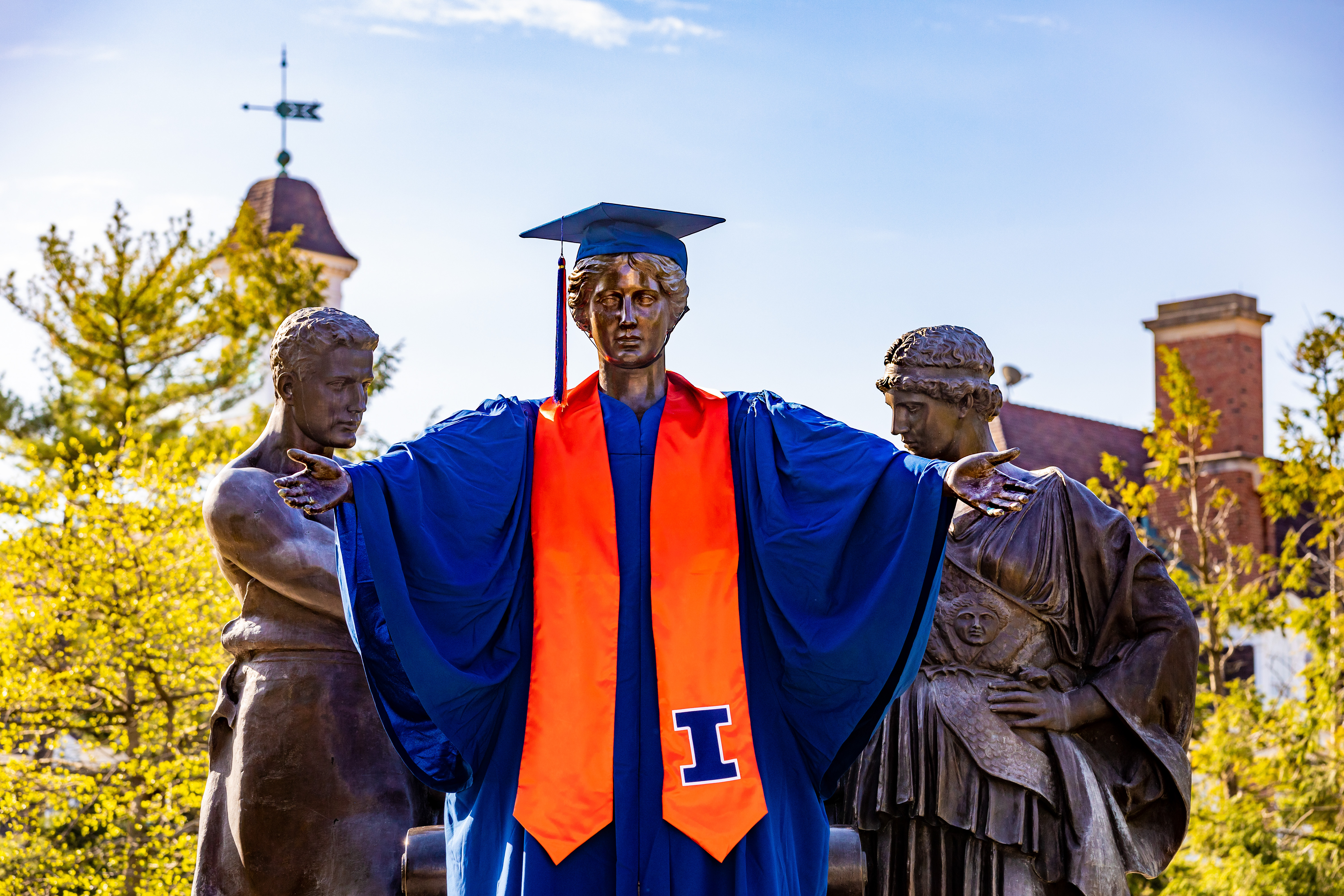 Alma statue wears cap and gown on a spring day.