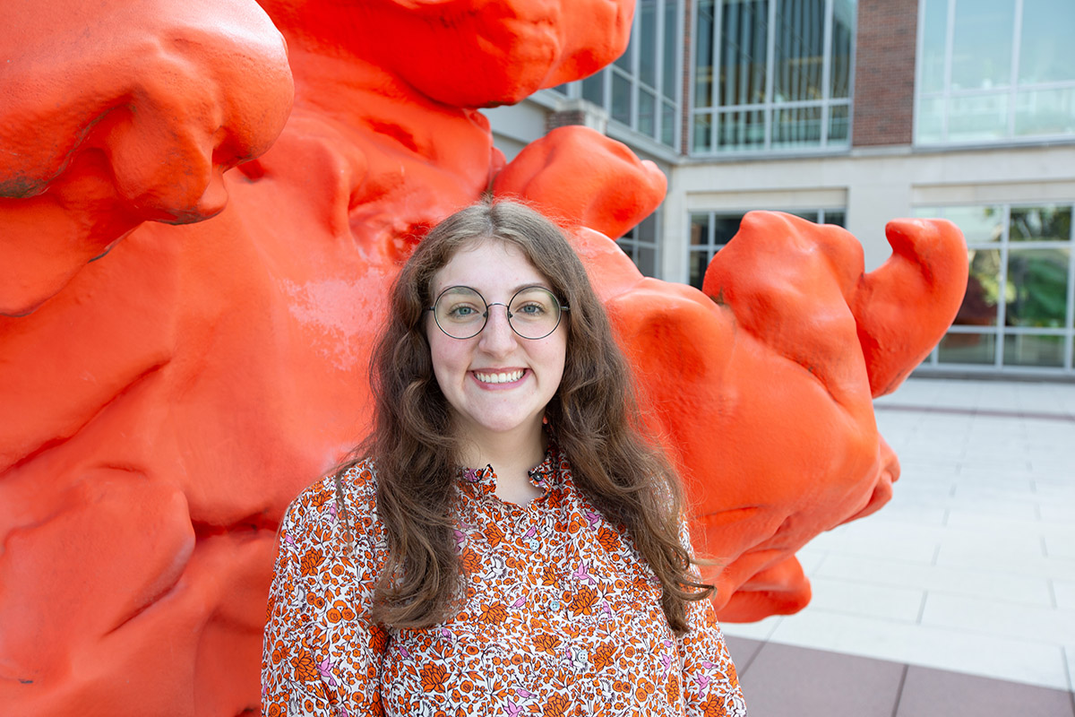 MCB major Catherine Koterba stands outside an orange sculpture at the Carl R. Woese Institute for Genomic Biology