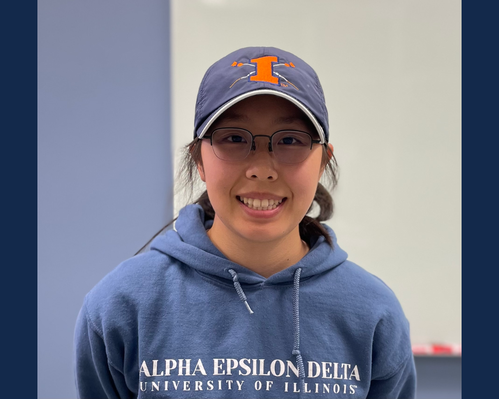 A smiling woman wearing glasses and a baseball cap.