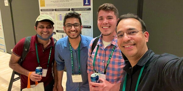Members of Kalsotra Lab pose for selfie in front of a poster presentation board.