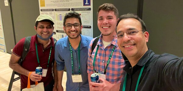 Members of Kalsotra Lab pose for selfie in front of a poster presentation board.