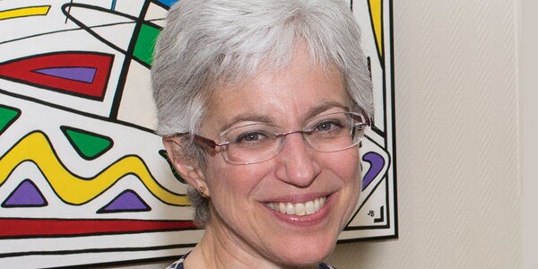 Deborah Paul smiles in front of a painting.