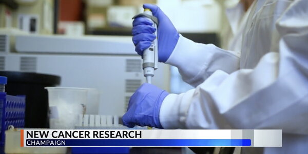 A scientist in a white lab coat pipetting
