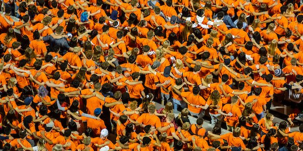 group of students in orange shirts put arms around each other