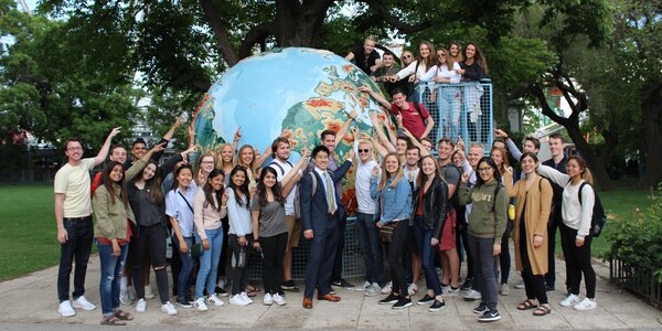 Study abroad students pose near a large model of a globe.