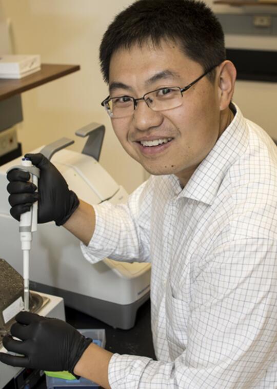 Kai Zhang holds piping tool in lab.