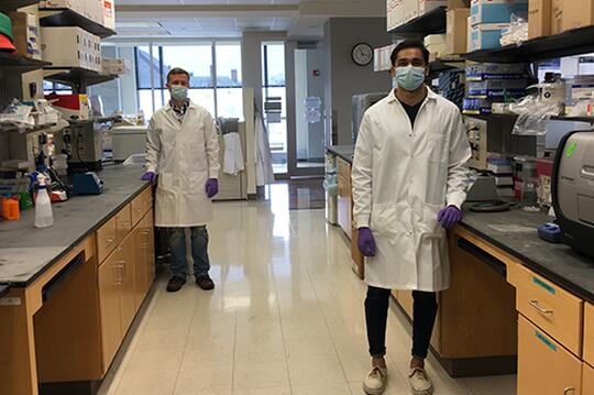 Laboratory technicians Justin Lange, left, and Akanksh Shetty observe social distancing while creating Viral Transport Media in the Carl R. Woese Institute for Genomic Biology. The fluid is used to preserve patient test samples for COVID-19. (Photo by Ann Hyoung Sook.)