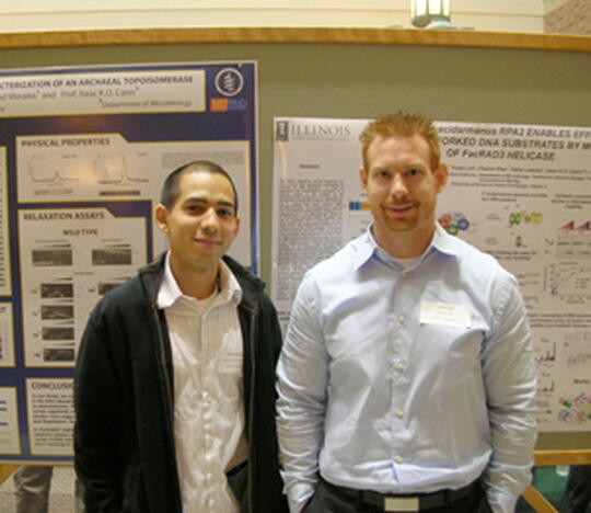 Biochemistry graduate students Raymond Morales and Robert Pugh stand in front of their posters during the first poster presentation.