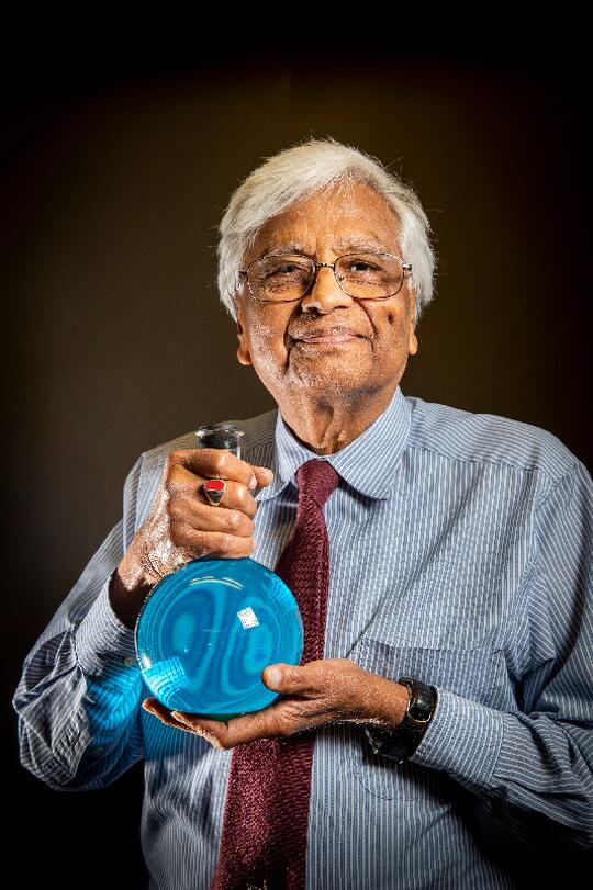 Govindjee holds a flask with a copper sulfate solution that he used in experiments to filter out the heat from white light.