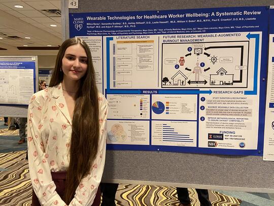 Milica Barac stands in front of a research presentation poster.