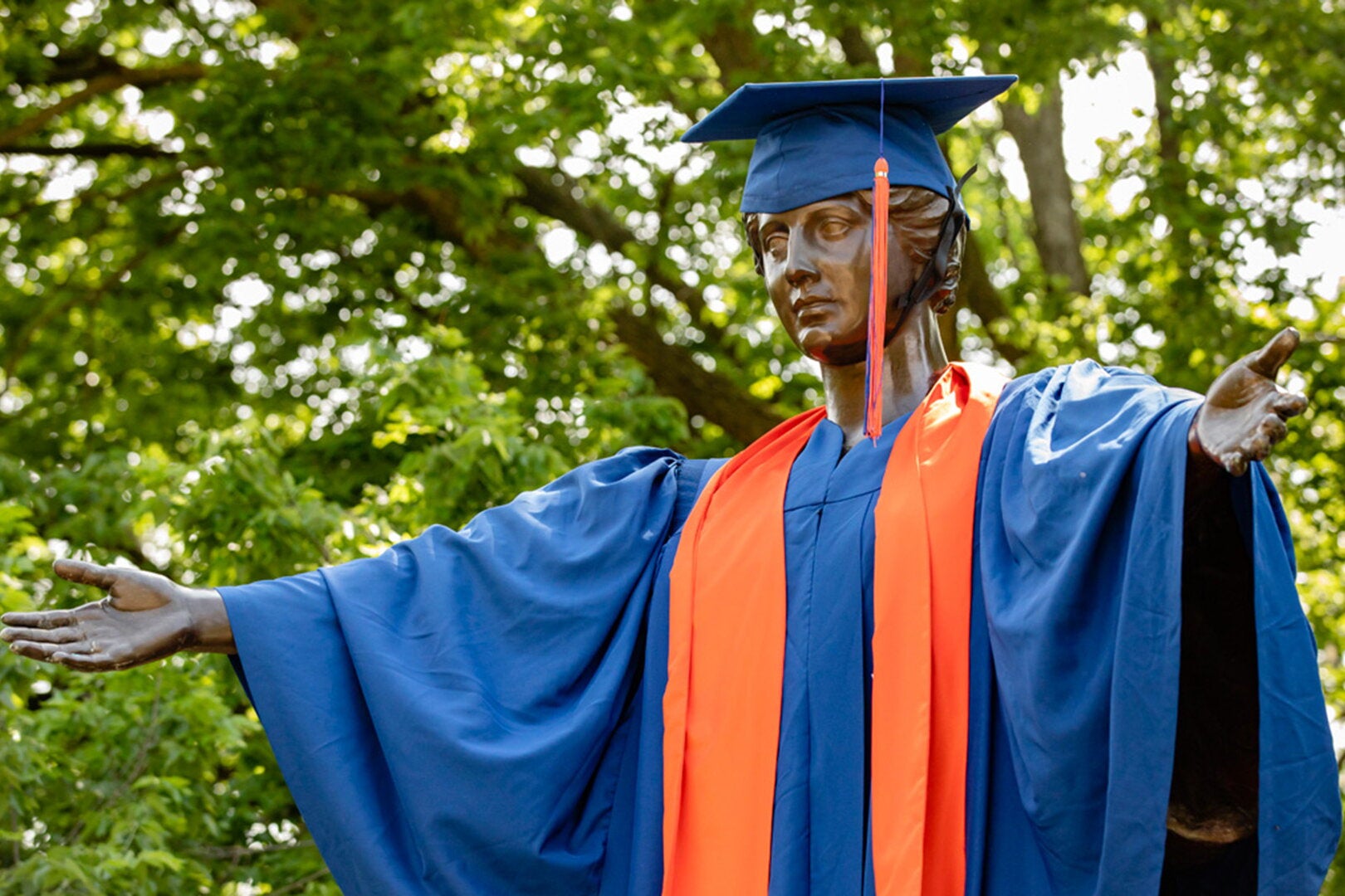Alma is dressed in orange and blue cap and gown.