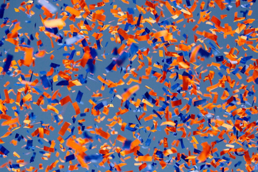 Blue and orange confetti flies in the air.