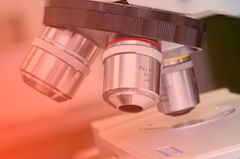 A tight shot of a microscope with a soft orange gradient layer.
