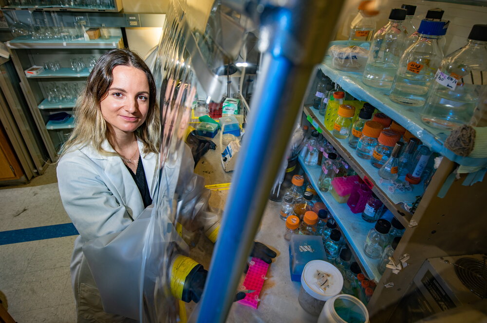 Stefanie Eben looks up at the camera with a smile. She is standing next to an anaerobic chamber.