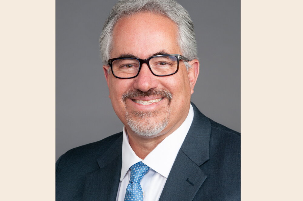 A smiling man in glasses and a suit.