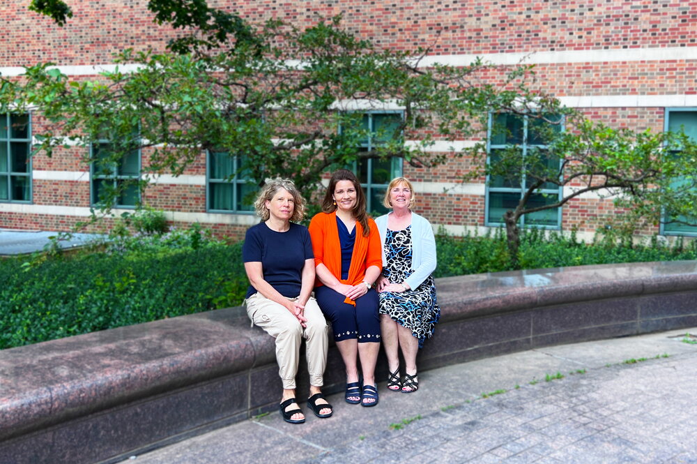 Three women sitting on a bench.