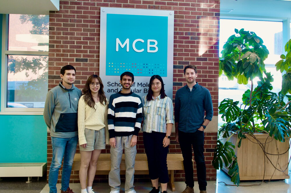 5 people standing in front of a sign reading, "MCB." 