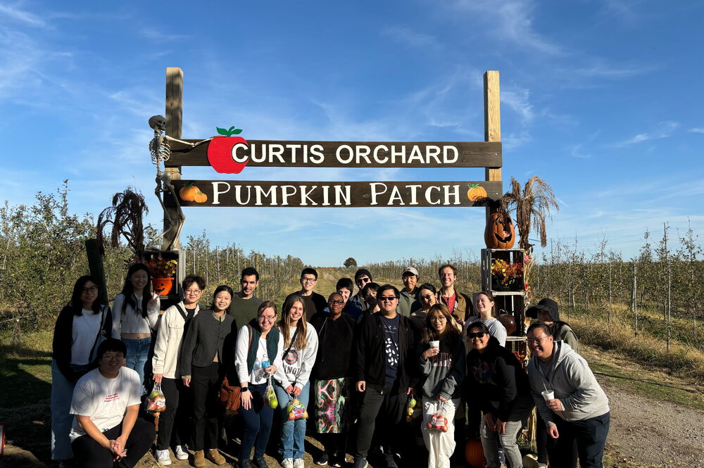 A group of students standing in front of an apple orchard.