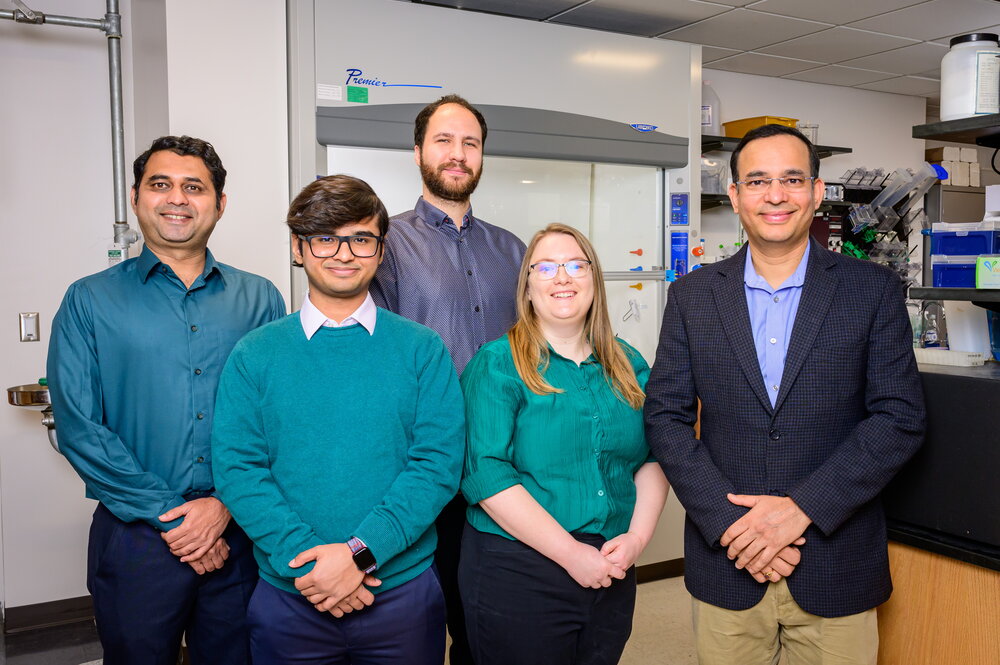 5 researchers standing in a laboratory. 