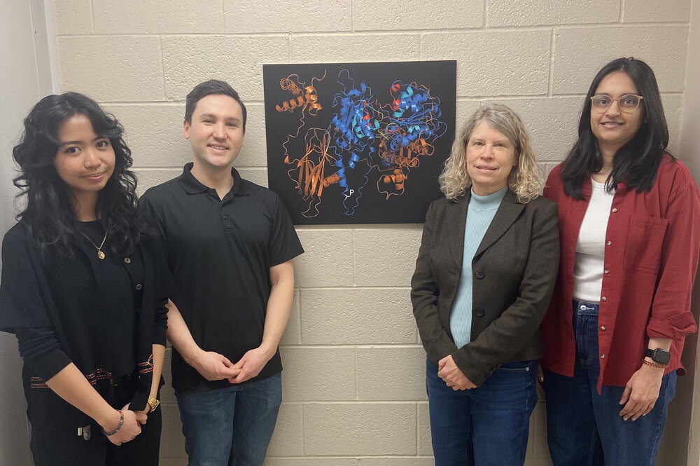 4 people standing next to a poster.