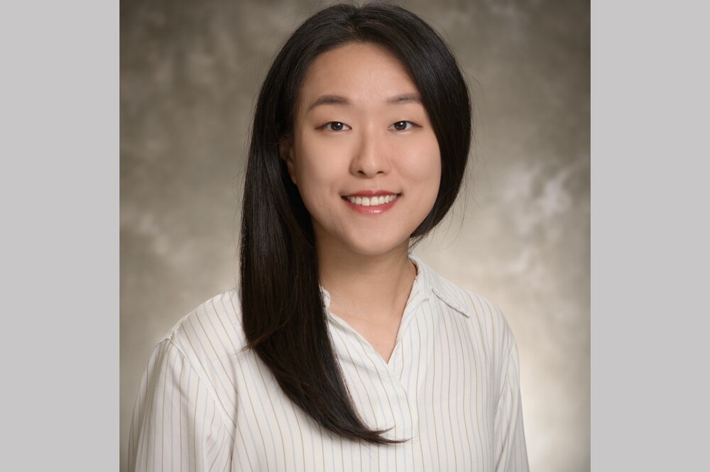 Woman with long black hair wearing white long sleeved shirt