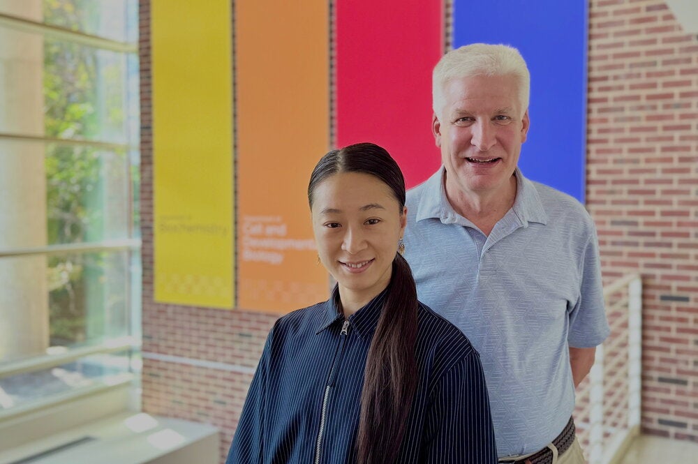 Man and woman stand and smile while in the atrium of laboratory building