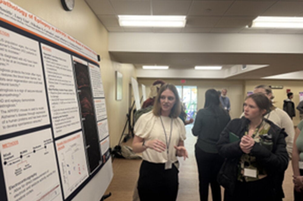 Undergraduate presents research poster to attendee of neuroscience conference