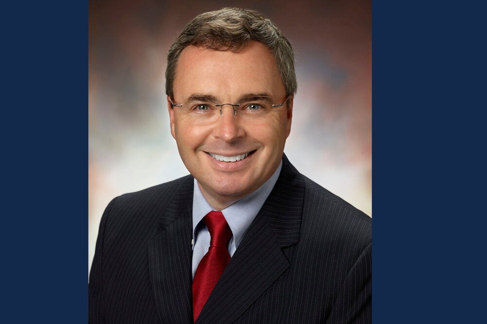 Guy Padbury in a dark suit and red tie