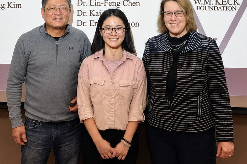 Lin-Feng Chen and Susan Martinis stand in front of projector screen with Phd student Xiaodan Lin