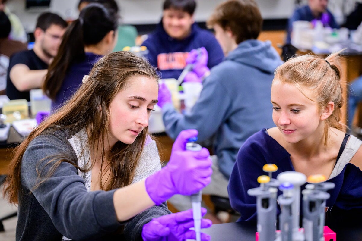 Two students pipetting in a lab.
