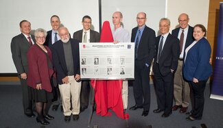 Faculty gather around the plaque honoring UIUC as a milestone in microbiology.