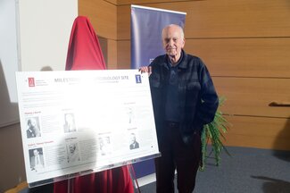 Professor Ralph Wolfe poses near the plaque.