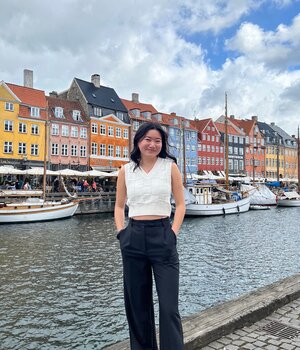 Amelia (Ji Ji) Steinlein poses on the riverfront in Stockholm, with brightly-colored row homes in the background.