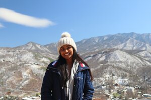 Shreya Jeyakumar stands outside with a background of snowy mountains.
