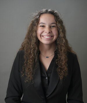 woman with brown hair and black shirt smiles for camera