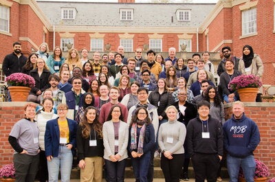 A group of microbiology scholars gather on steps of the Allerton mansion