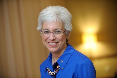 Woman with short white hair and eyeglasses wears blue shirt