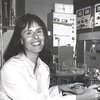 In a black and white photo, Benita S. Katzenellenbogen smiles for camera while sitting in lab.
