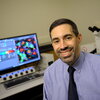 Dan Llano sits at a desk with a computer in the background. 