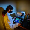 Neha Arun reviews imaging of host-pathogen interactions in a darkly lit room, with her face illuminated by the screen.