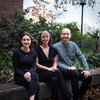 Authors Nicole Godellas, Gisela Cymes, and Claudio Grosman sit together in a row outside, smiling. 