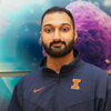 Headshot of Jay Sonalkar in front of a wall with illustrations of cells. He is wearing a U of I zip-up jacket.