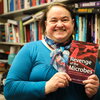 Microbiology professor Brenda Wilson stands in her office holding a copy of the book, Revenge of the Microbes