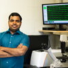 a man in a blue shirt standing in front of a monitor.